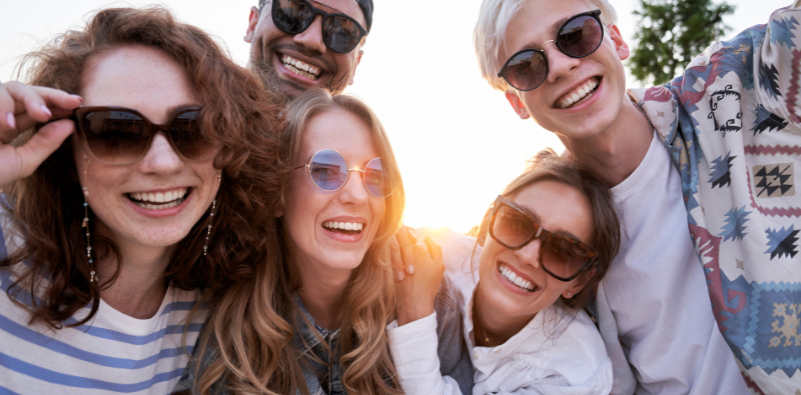A group of friends wearing sunglasses, smiling.
