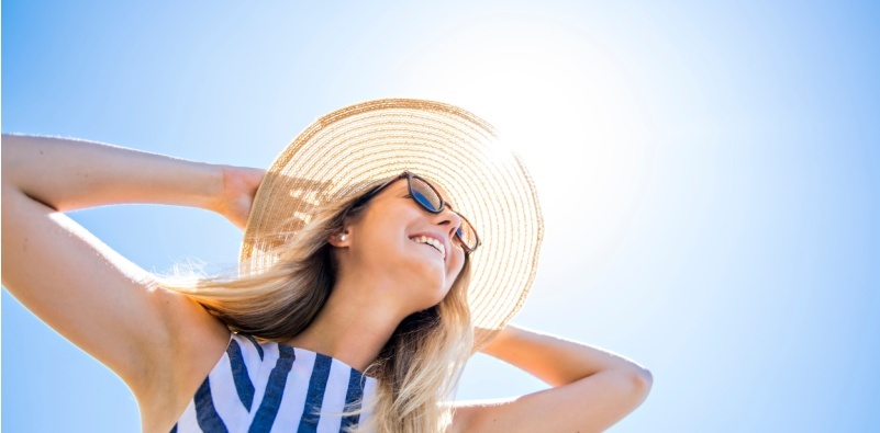 A woman wearing sunglasses and a hat, outdoors in the sun.