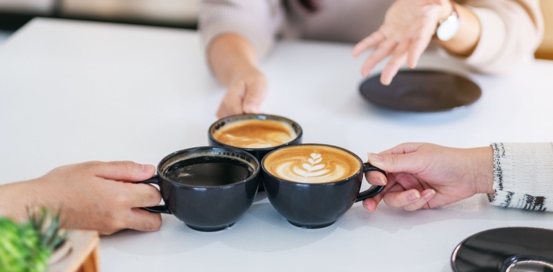 A close-up image of people enjoying drinks in a coffee shop environment.