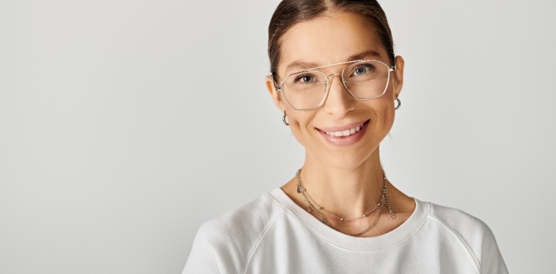 A young woman in a white t-short wearing a pair of metal aviator style glasses.