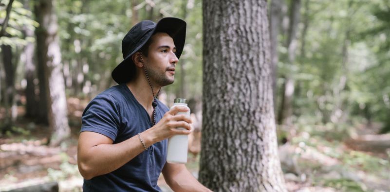 A man drinking from a white water bottle on a hike
