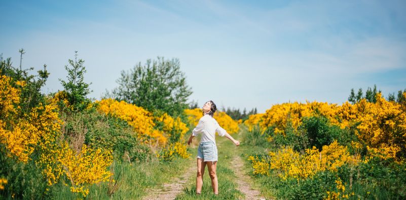 A woman dancing around the field surrounded by yellow flowers