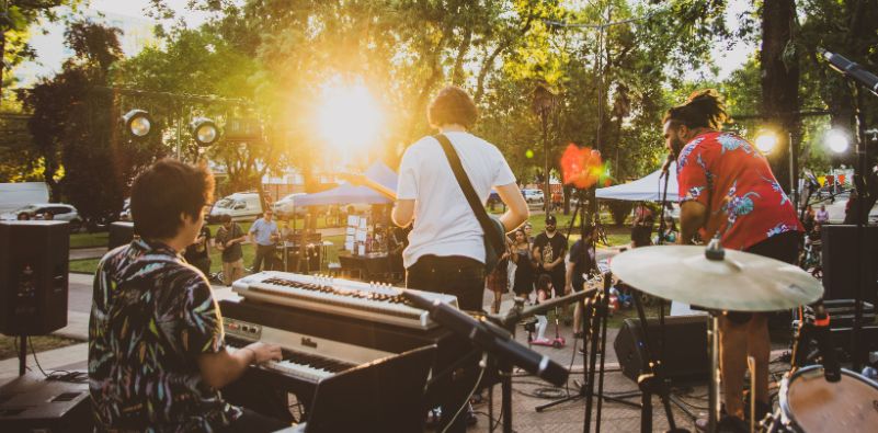 A band playing instruments outdoors to a crowd of people