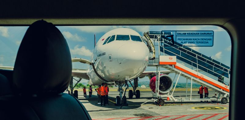 A commercial plane connected to its boarding stairs at the airport.
