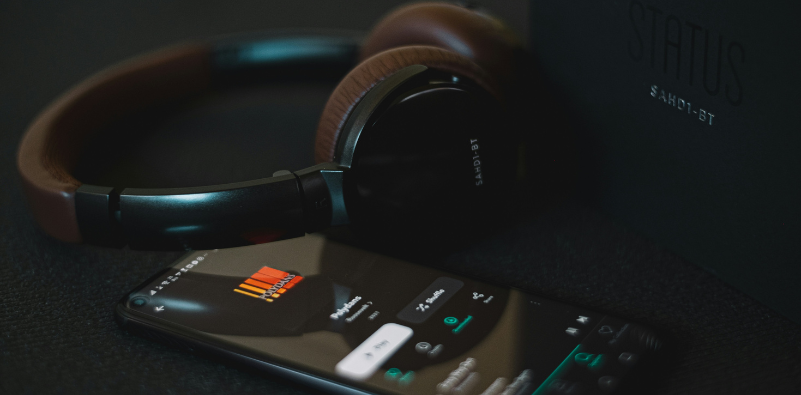 A smartphone displaying a playlist beside a pair of headphones